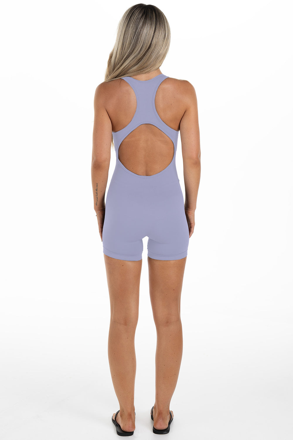 Lady in a purple jumpsuit made for sports, back angle
