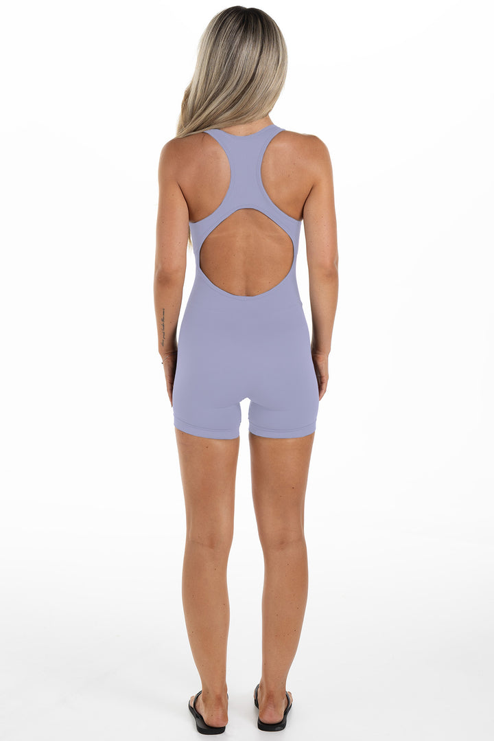 Lady in a purple jumpsuit made for sports, back angle